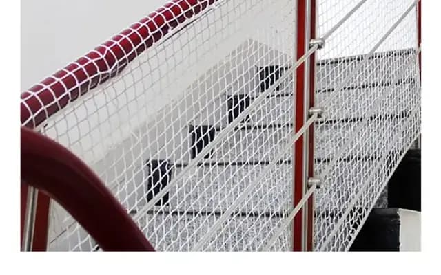 White netting secured along an indoor staircase railing