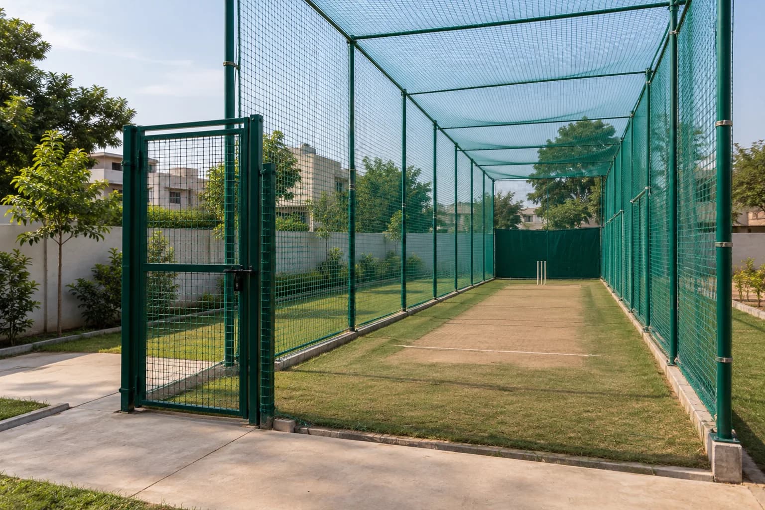 Cricket practice lane with side netting, overhead coverage and an entrance gate