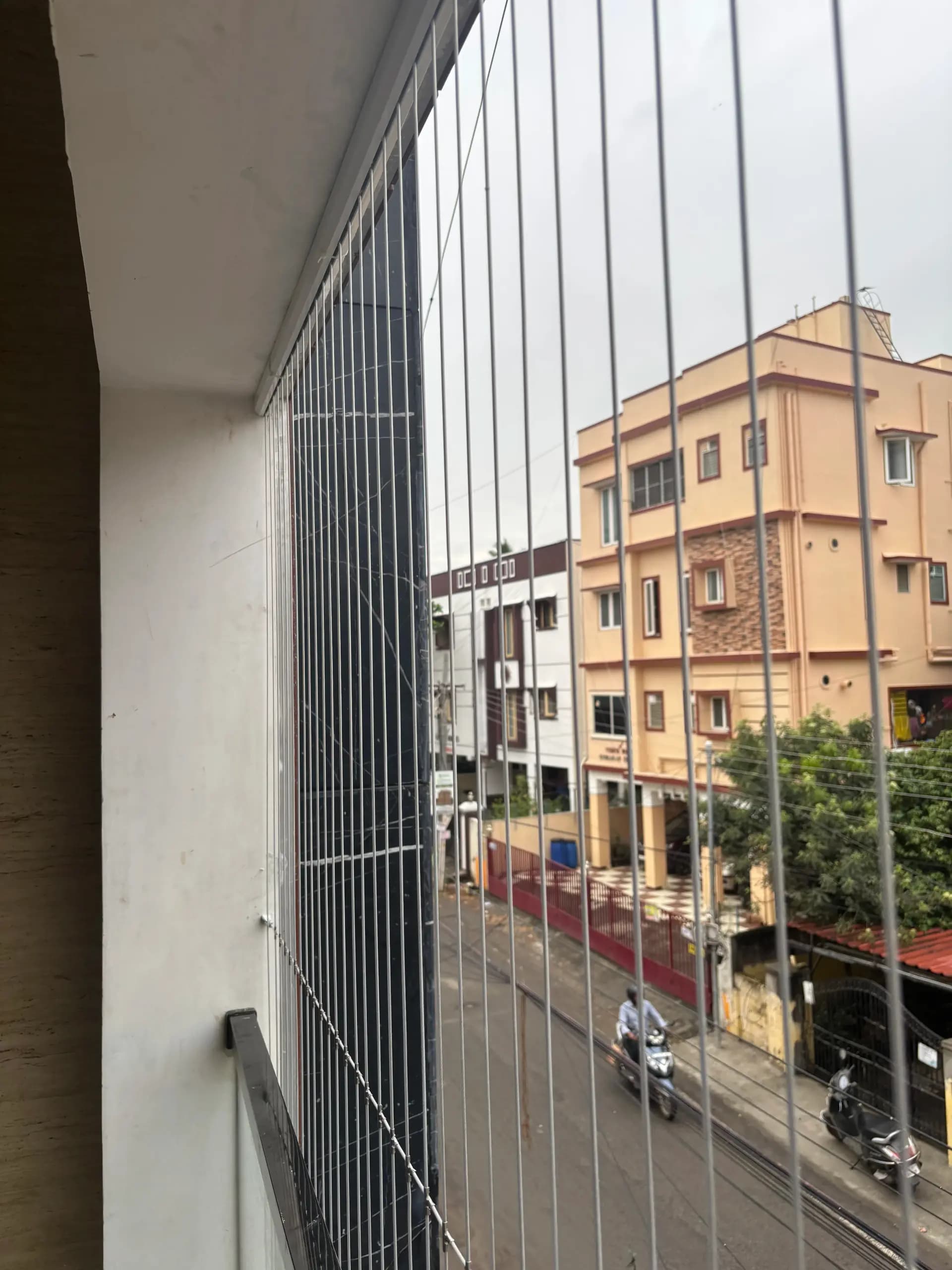 Close view along vertical stainless cables and an upper channel at a residential balcony
